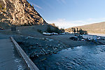 This is the home base for the Chitina dipnetting fishery that supplies thousands of Alaskans with much (if not most) of their annual protein.  Many people pay a jetboat charter to ferry them down to prime spots in the canyon, and ferry their hundreds of pounds of fish back up.  Others follow the trail to which this bridge leads and negotiate the steep canyon wall themselves, with their fish, and haul them back with the help of an ATV. From the Copper River in Alaska.