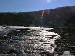 A small tributary tumbles toward a large Catskill river. From the West Branch of the Delaware River in New York.