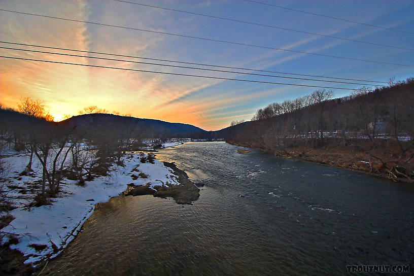 A late winter sunset radiates over a Catskill ridge.  This picture is taken near a popular landing on one of the main tailwaters. From the West Branch of the Delaware River in New York.